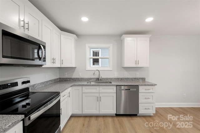 kitchen with a sink, appliances with stainless steel finishes, light wood-style flooring, and white cabinets