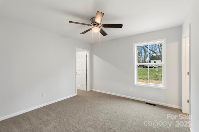 spare room with visible vents, carpet flooring, a ceiling fan, and baseboards