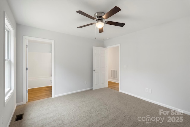 unfurnished bedroom featuring multiple windows, carpet, visible vents, and baseboards