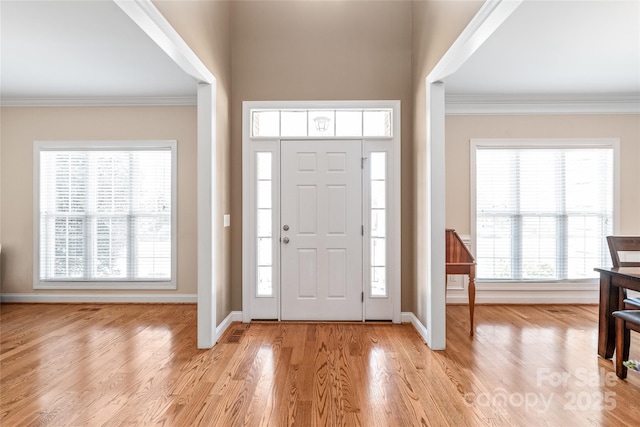 entrance foyer featuring crown molding, plenty of natural light, and light wood-type flooring