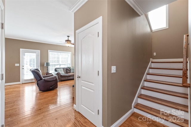 stairs featuring baseboards, crown molding, ceiling fan, and wood finished floors