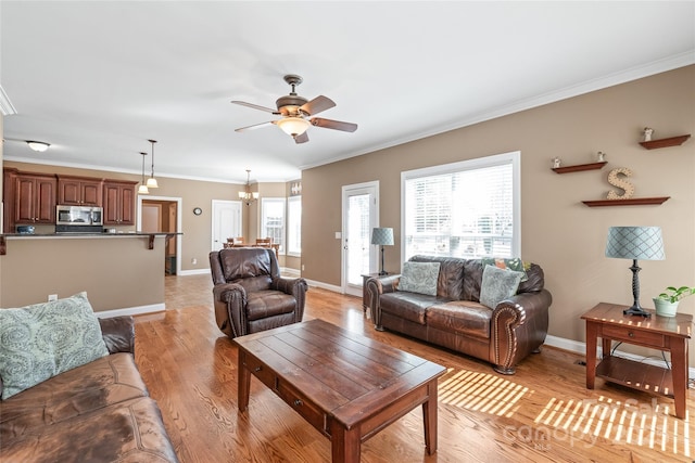 living area featuring baseboards, a ceiling fan, light wood-type flooring, and ornamental molding