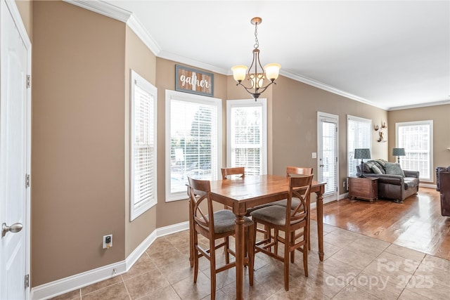 dining area featuring an inviting chandelier, light tile patterned floors, baseboards, and ornamental molding