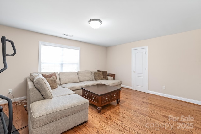 living area with light wood-style flooring, visible vents, and baseboards