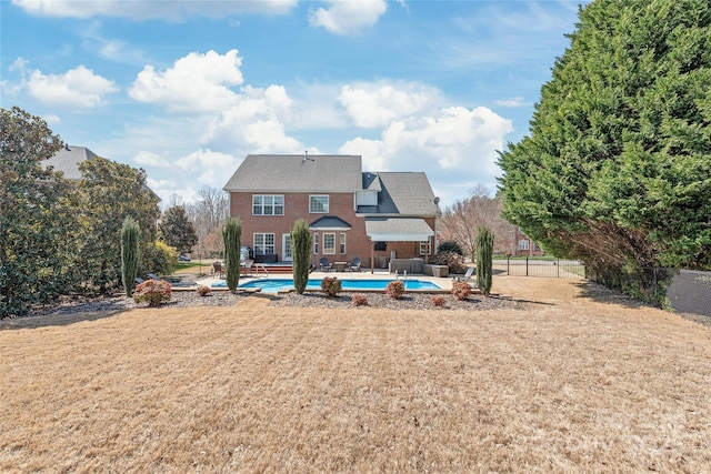 back of property featuring a lawn, an outdoor pool, a patio, and fence