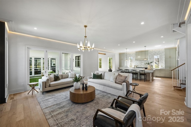 living room with recessed lighting, an inviting chandelier, and light wood-style floors
