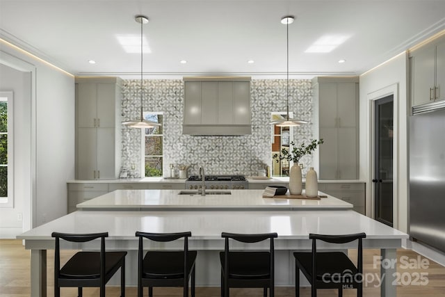 kitchen featuring tasteful backsplash, gray cabinetry, built in refrigerator, light wood-style flooring, and a sink