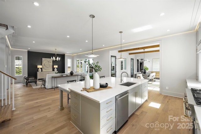 kitchen with a center island with sink, dishwasher, light wood-style flooring, an inviting chandelier, and a sink