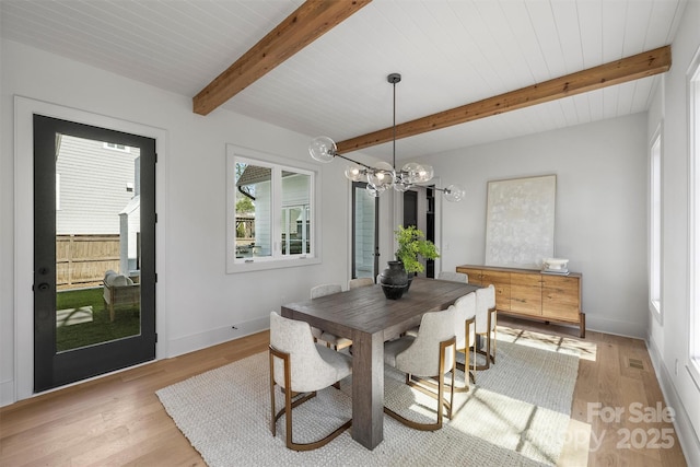 dining room with beam ceiling, a notable chandelier, baseboards, and light wood-type flooring
