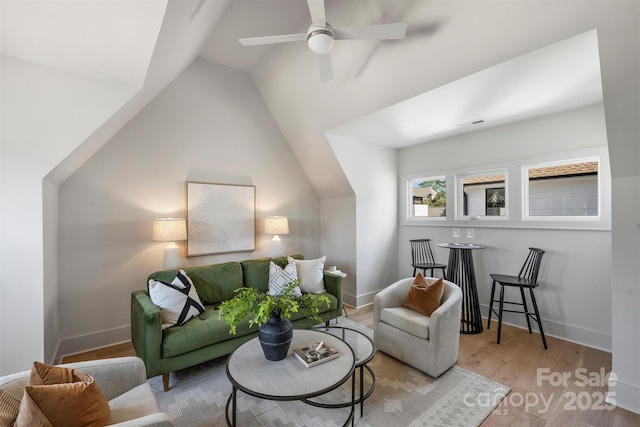 living room featuring vaulted ceiling, wood finished floors, baseboards, and ceiling fan