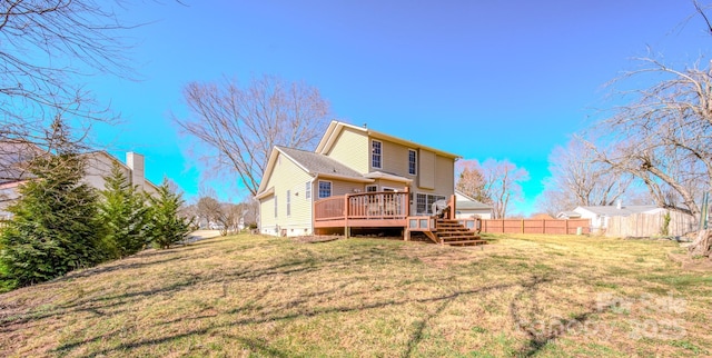 back of property with a lawn, a deck, and fence