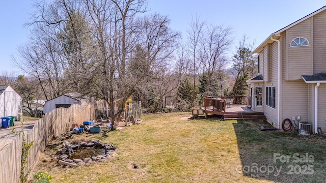 view of yard featuring central AC unit, a wooden deck, and fence