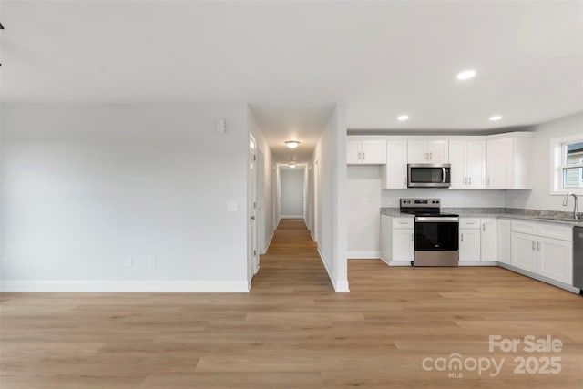 kitchen featuring baseboards, light wood-type flooring, recessed lighting, appliances with stainless steel finishes, and white cabinetry