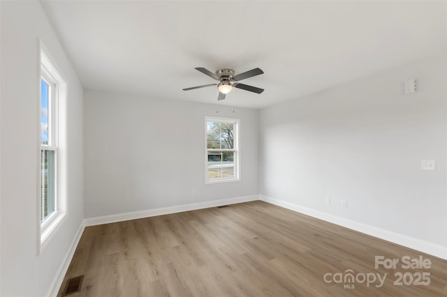 spare room with visible vents, ceiling fan, baseboards, and wood finished floors