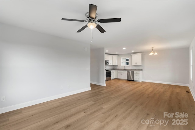 unfurnished living room with visible vents, light wood-style flooring, ceiling fan with notable chandelier, recessed lighting, and baseboards