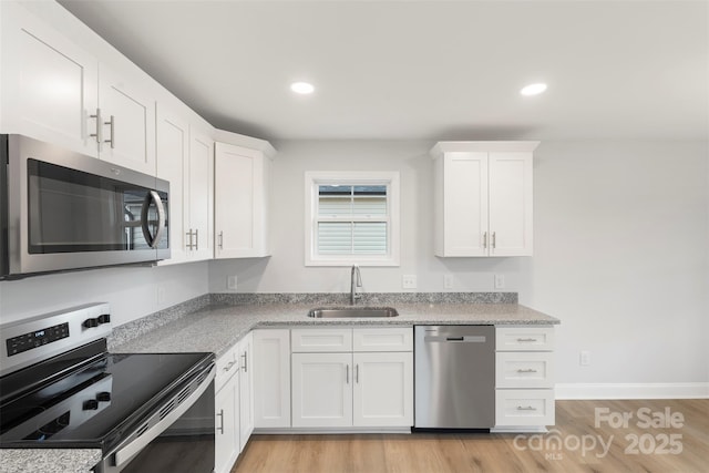 kitchen with light wood-style flooring, a sink, recessed lighting, stainless steel appliances, and white cabinets