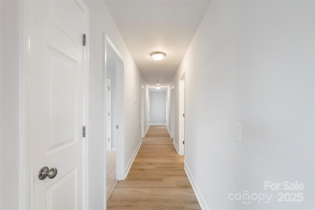 hallway featuring baseboards and light wood finished floors