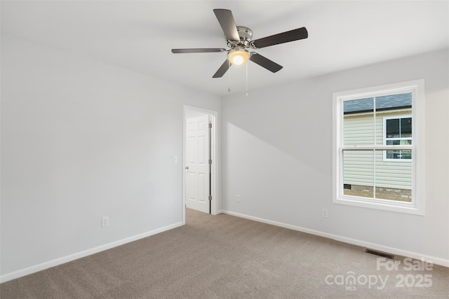 empty room featuring visible vents, light colored carpet, baseboards, and ceiling fan