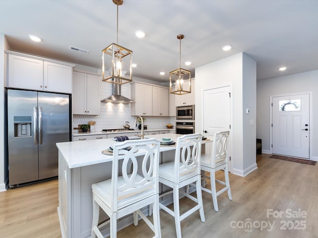 kitchen with visible vents, backsplash, light countertops, light wood-style floors, and stainless steel appliances