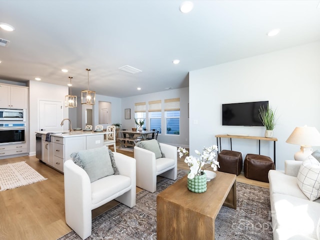 living area with light wood finished floors, visible vents, and recessed lighting