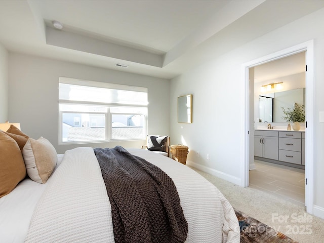 bedroom with visible vents, baseboards, a tray ceiling, light carpet, and a sink