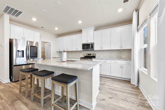 kitchen featuring visible vents, a sink, tasteful backsplash, white cabinetry, and stainless steel appliances