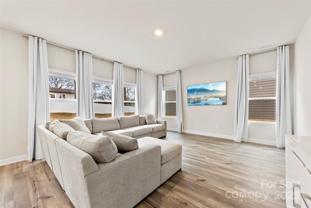 living room featuring recessed lighting, baseboards, and light wood-style floors