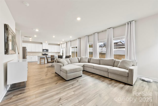 living area featuring recessed lighting, light wood-type flooring, and baseboards