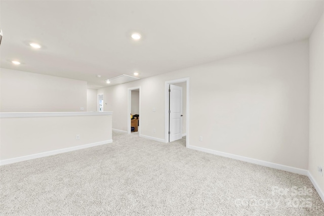 spare room featuring recessed lighting, light colored carpet, attic access, and baseboards