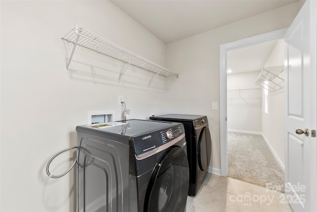 washroom with light carpet, washer and dryer, light tile patterned flooring, baseboards, and laundry area