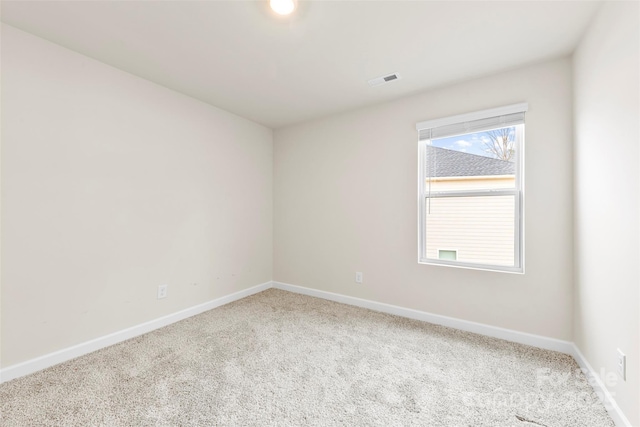 carpeted spare room featuring visible vents and baseboards