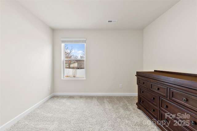 spare room featuring light carpet, visible vents, and baseboards