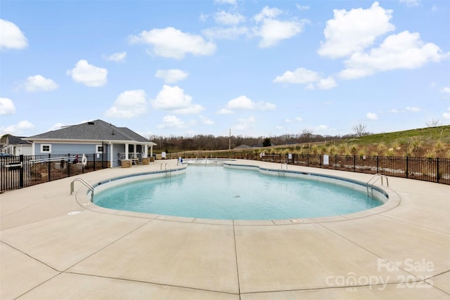 community pool with a patio and fence