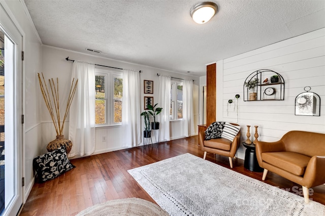 living area with visible vents, a textured ceiling, and hardwood / wood-style floors