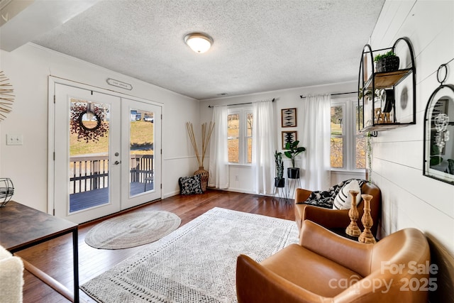 living area with wood finished floors, french doors, and a textured ceiling