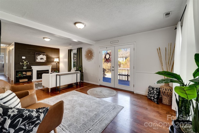 living area featuring visible vents, a fireplace, hardwood / wood-style flooring, french doors, and a textured ceiling