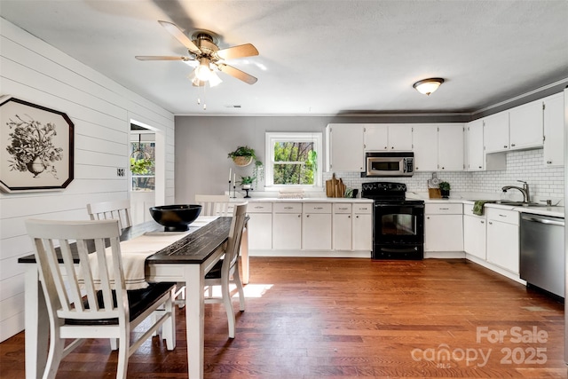 kitchen featuring light countertops, decorative backsplash, appliances with stainless steel finishes, dark wood-style floors, and a sink