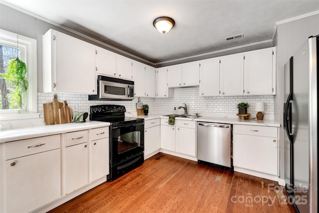 kitchen with backsplash, crown molding, appliances with stainless steel finishes, dark wood-style floors, and a sink