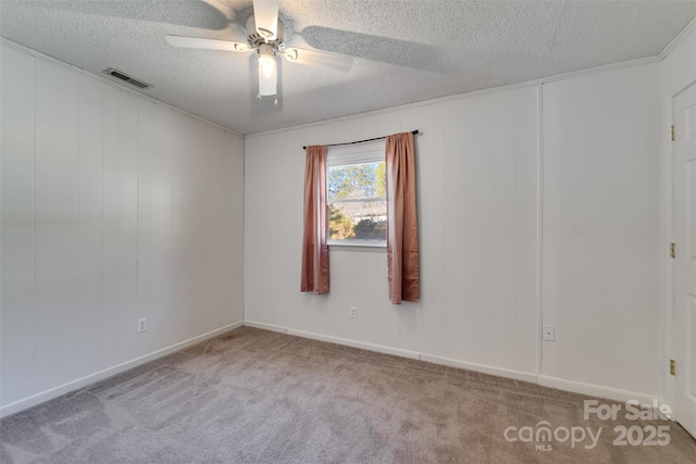 carpeted spare room with ceiling fan, visible vents, and a textured ceiling