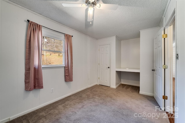 unfurnished bedroom featuring baseboards, carpet floors, a textured ceiling, and ceiling fan