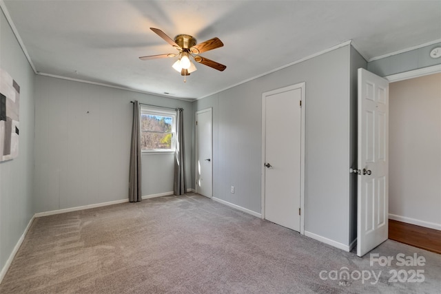 unfurnished bedroom with a ceiling fan, baseboards, carpet, and crown molding