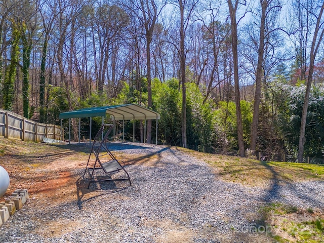 view of yard featuring a detached carport, fence, and driveway