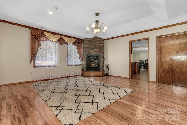 unfurnished living room featuring a tray ceiling, wood finished floors, baseboards, and a chandelier