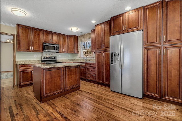 kitchen with light stone countertops, wood finished floors, a textured ceiling, stainless steel appliances, and a sink