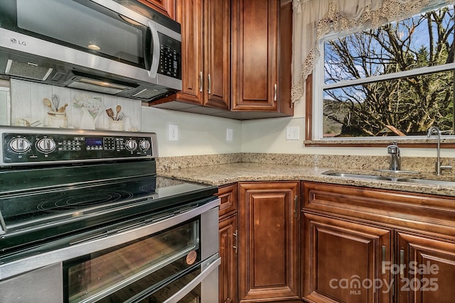 kitchen with a sink, light stone countertops, and stainless steel appliances