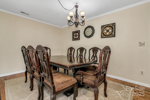 dining area featuring visible vents, baseboards, ornamental molding, an inviting chandelier, and wood finished floors