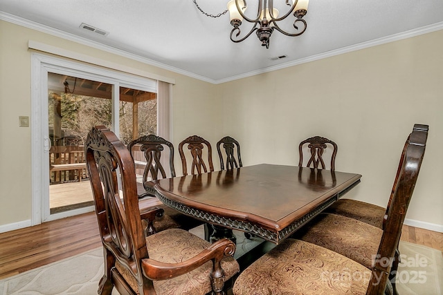 dining area featuring visible vents, a notable chandelier, wood finished floors, and crown molding