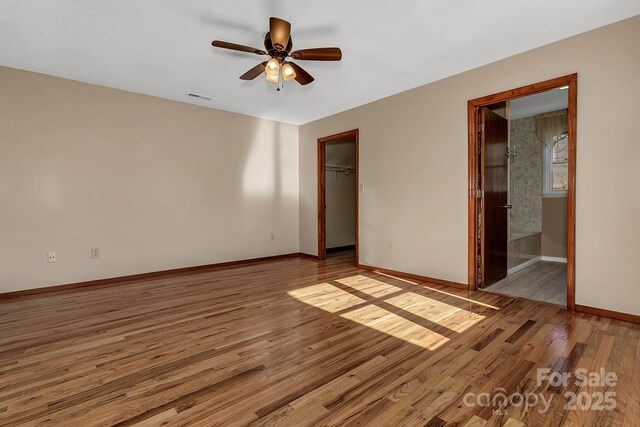 unfurnished bedroom with visible vents, baseboards, light wood-style floors, a closet, and a walk in closet