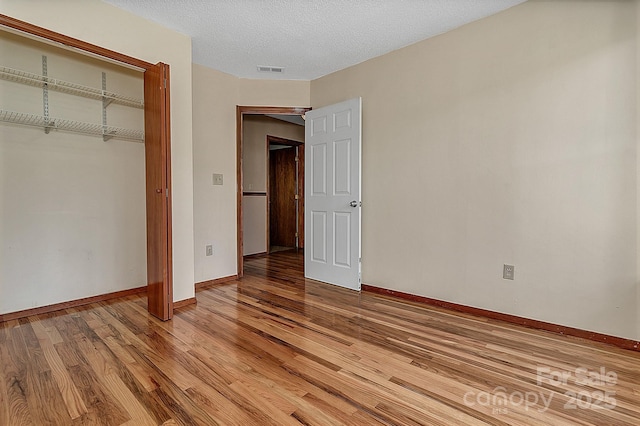 unfurnished bedroom with visible vents, baseboards, light wood-style floors, a closet, and a textured ceiling