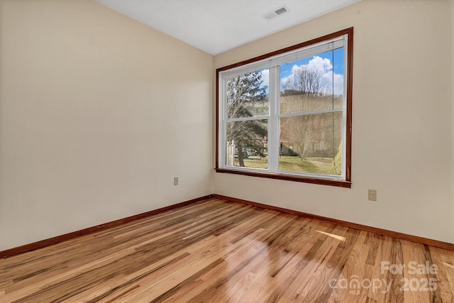 unfurnished room featuring visible vents, baseboards, vaulted ceiling, and light wood finished floors